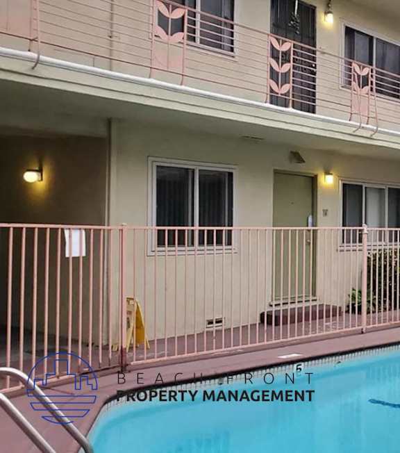 A pool with a hot tub and lounge chairs in front of a building.