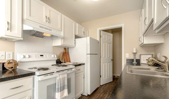 A kitchen with white cabinets and a black countertop.