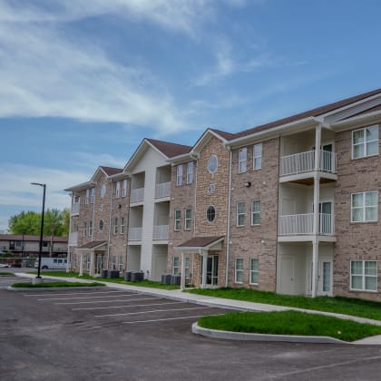 an exterior view of an apartment building with a parking lot