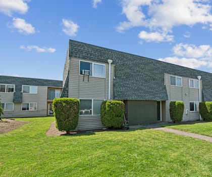 a row of houses with a green lawn and a sidewalk