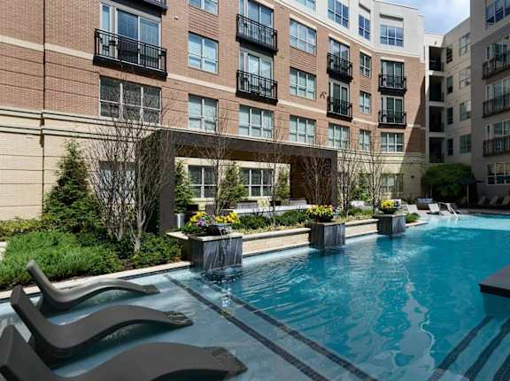 A swimming pool surrounded by a black bench and a building in the background.
