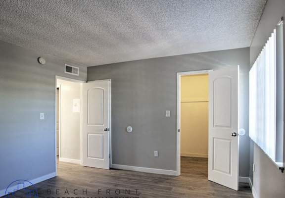 A room with a white door and a window on the right side.