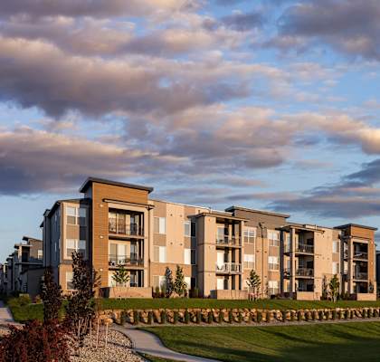 A row of modern apartment buildings are lined up on a grassy area.