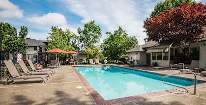 Sunstone Parc apartments pool, spa, lounge chairs, tables and umbrellas 