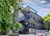 Thumbnail 22 of 30 - Contemporary apartment building with black metal staircases, balconies, and mature trees surrounding the property at 1443 Elizabeth in Denver, CO