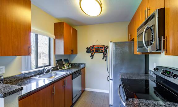 A kitchen with a black fridge and stove at The Lakes Apartments in Bellevue, 98007