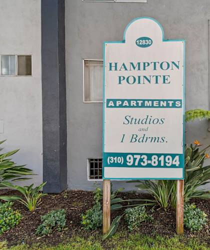 A sign for Hampton Pointe Apartments is in front of a building.