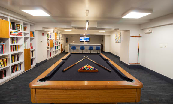 A pool table in a room with bookshelves and a TV at The Argonne Apartments, Washington, DC, 20009