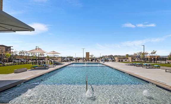 A large outdoor swimming pool with a fountain in the middle.