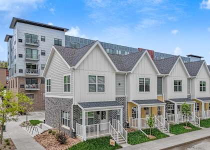 A row of houses with a sidewalk in front.