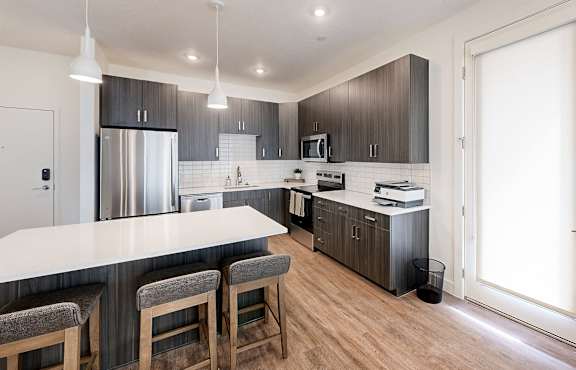 A modern kitchen with a bar area and wooden floors.