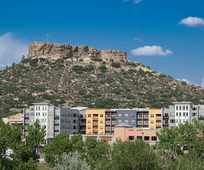 A mountain with a rocky peak and buildings in front of it.