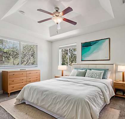 A bedroom with a bed, nightstand, and a ceiling fan.