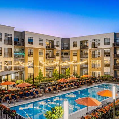 an apartment building with a swimming pool at dusk