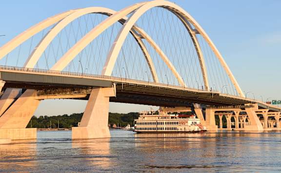 A large white arch bridge spans a body of water with a boat underneath. at Kimberly Club Apartments, Davenport, 52807