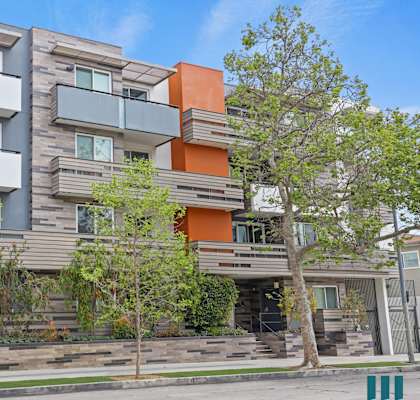 the facade of a condo building with trees in front of it
