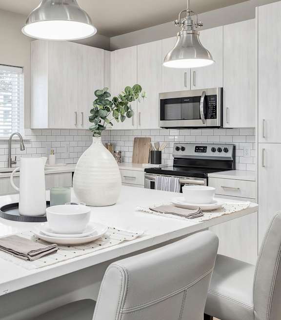 A modern kitchen with a white table and grey chairs.