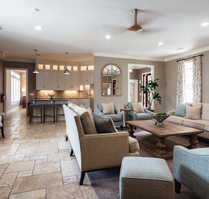 A spacious living room with a variety of seating options and a kitchen area in the background.