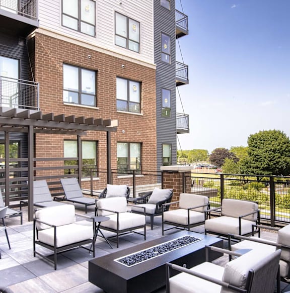 A patio with a table and chairs is in front of a brick building.