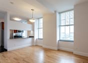 Thumbnail 18 of 23 - A large empty room with wooden floors and a window with blinds.