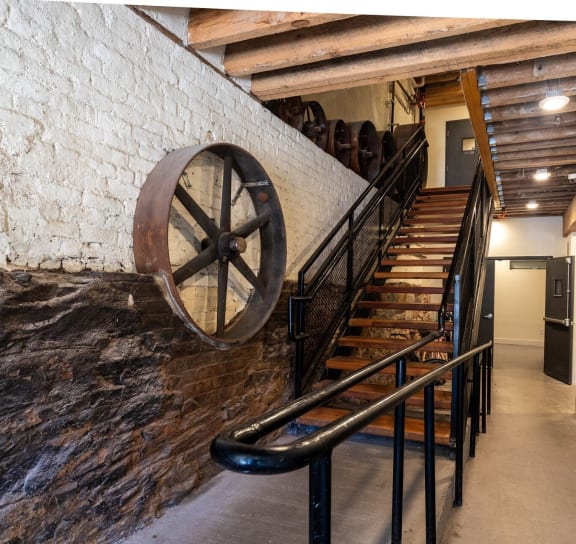 a staircase with a water wheel next to a brick wall