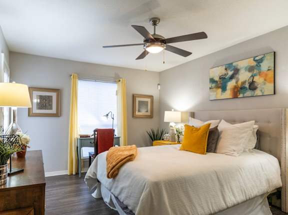 A bedroom with a large bed and a ceiling fan.
