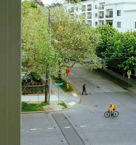 a view from a window of a city street with a cyclist and a person riding