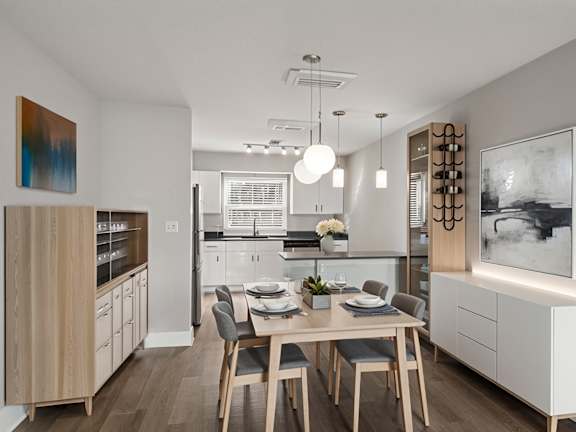 Mandarin Bay Apartments dining area and kitchen with a light wood dining table, grey chairs, and a white cabinet on the right.