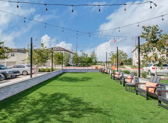 a yard with tables and chairs and a pool with grass