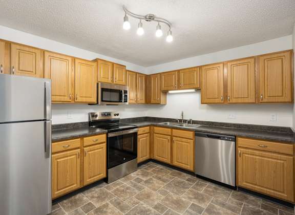 a kitchen with wooden cabinets and stainless steel appliances at Cityscape, St Louis Park, Minnesota