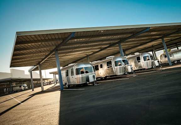 A row airstreams parked under an outdoor covered space.
