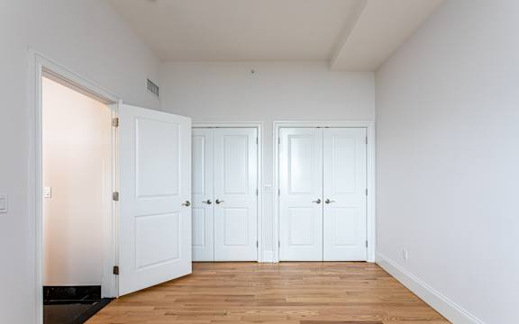Three white doors in a room with wooden floors.