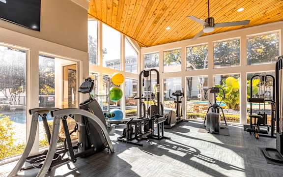A gym with a variety of equipment including treadmills, stationary bikes, and weight machines.
