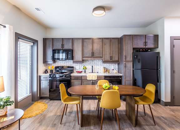 Studios in Butchertown KY - Martin on Main - Dine_in Kitchen with Brown Cabinets, Black Appliances, and Dining Room Table with Chairs.