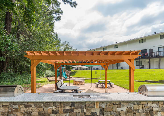 a backyard with a wooden pavilion with a picnic table and a swing