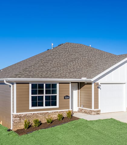 the front of a home with a green lawn and a blue sky