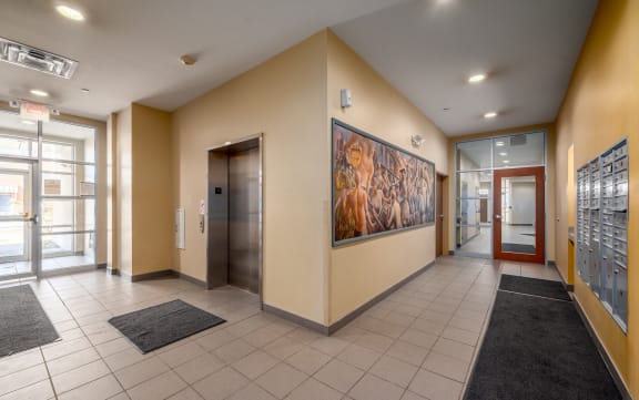 the lobby of a building with elevators and a large painting on the wall
