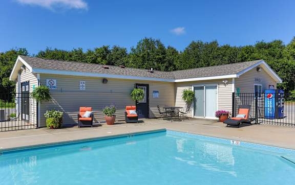 A pool in front of a small building with a sign on it.