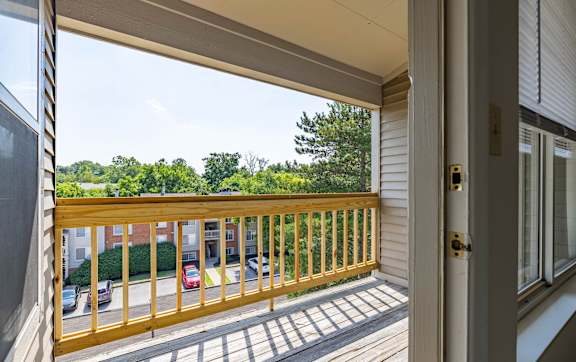 A view from a doorway looking out to a balcony with a railing and a parking lot.
