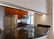 Thumbnail 17 of 23 - A kitchen with a granite counter top and stainless steel appliances.