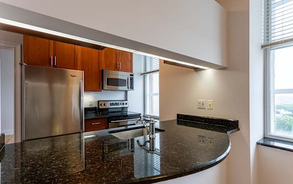 A kitchen with a granite counter top and stainless steel appliances.