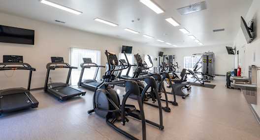 A gym with treadmills, elliptical machines, and other exercise equipment.