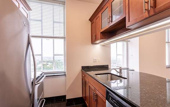 A kitchen with a refrigerator, sink, and cabinets.