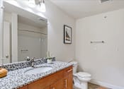 Thumbnail 4 of 8 - A bathroom with a toilet, sink, and mirror.