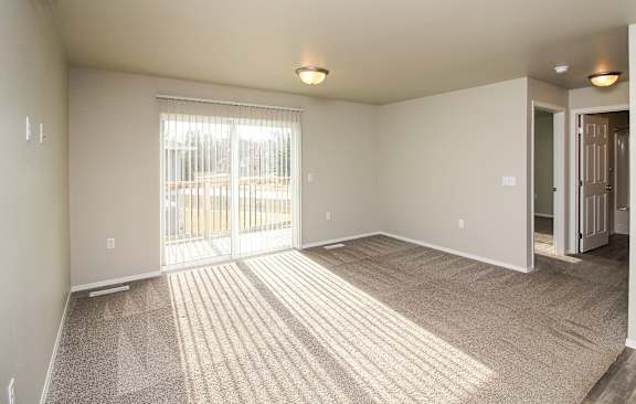 A room with a carpeted floor and a sliding glass door.