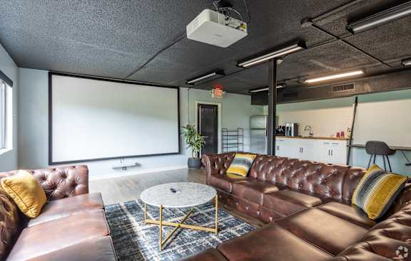 a living room with leather couches and a coffee table at Capital Flats & Magnolia Square Apartments, Raleigh, NC