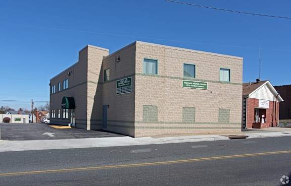 A grey building with a green awning sits on a street corner.