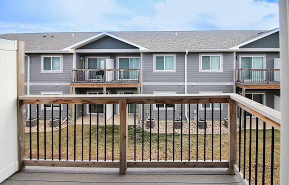 A balcony with a railing overlooking a grassy area and apartment buildings.
