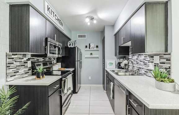 A modern kitchen with dark wood cabinets and stainless steel appliances.