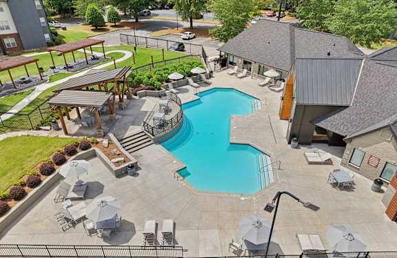 A large outdoor swimming pool surrounded by lounge chairs and umbrellas.